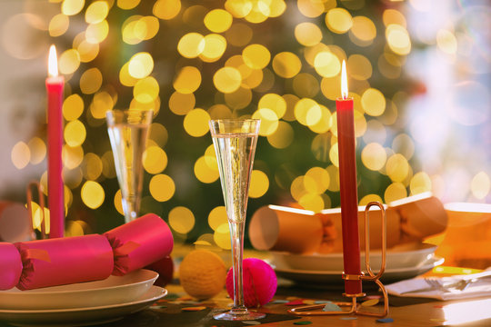 Champagne flutes, candles and Christmas crackers on dining table