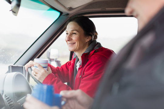 Smiling woman drinking coffee and driving motor home