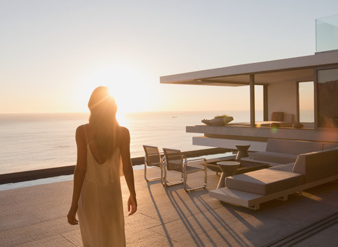 Woman walking on tranquil sunset modern, luxury home showcase exterior patio with ocean view