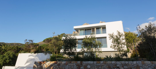 Trees around sunny modern modern luxury white home showcase exterior