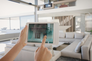 Personal perspective woman with digital tablet managing digital security system in modern, luxury home showcase interior living room