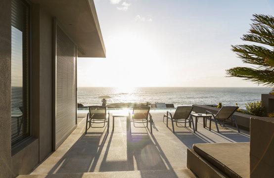 Lounge chairs on sunny luxury patio with ocean view