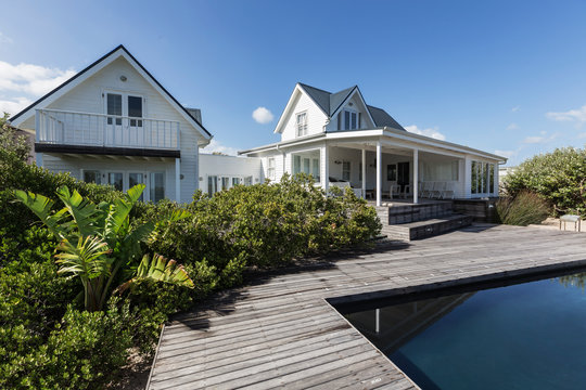 Sunny white modern home showcase exterior beyond swimming pool