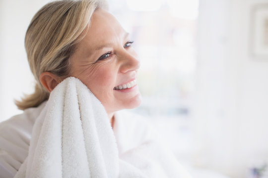 Smiling mature woman drying face with towel