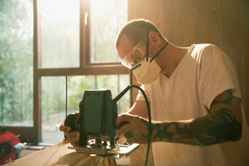 Construction worker with tattoo using electric saw to cut wood