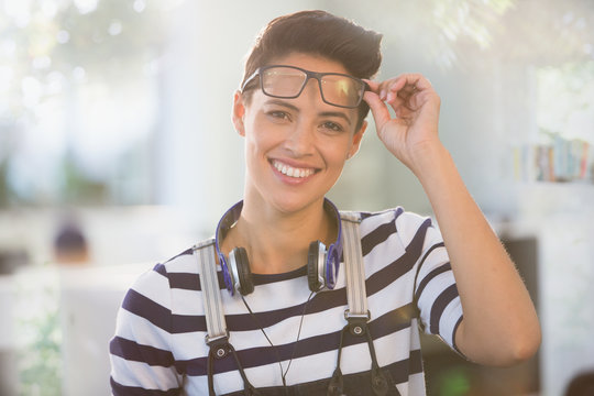 Portrait confident creative businesswoman with headphones and eyeglasses