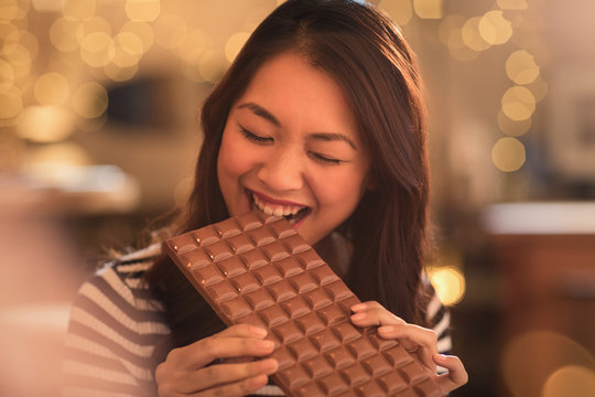 Woman with sweet tooth craving biting into large chocolate bar