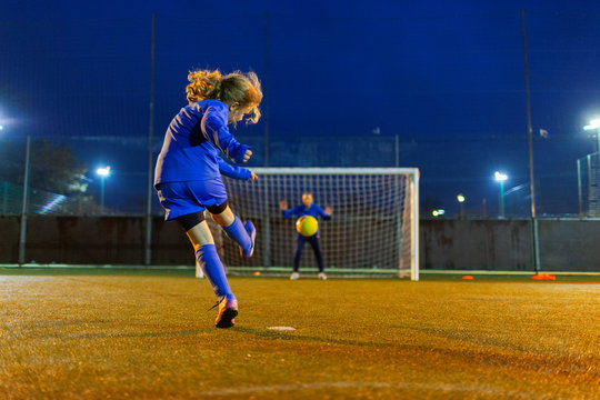 Girl soccer player kicking the ball toward goal