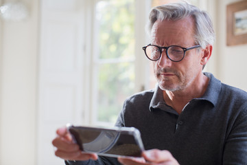 Focused mature man using smart phone
