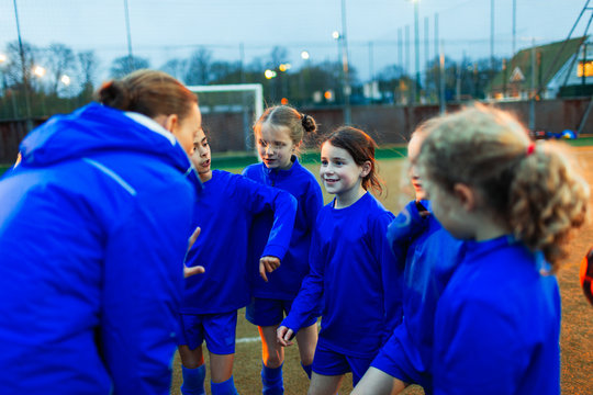 Girls soccer team listening to coach in huddle