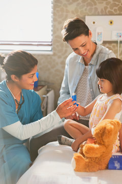 Female nurse showing girl patient inhaler in examination room