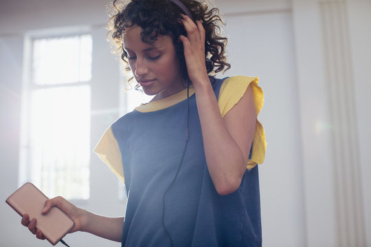 Young female dancer listening to music with headphones and mp3 player