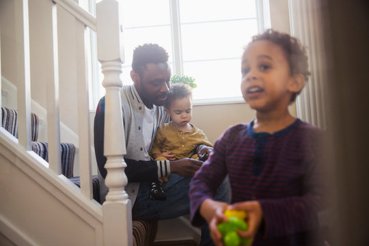 Father putting socks on baby son on stairs
