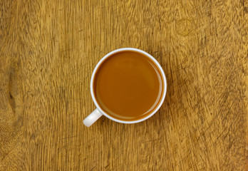 A cup of cocoa over wooden table, top view