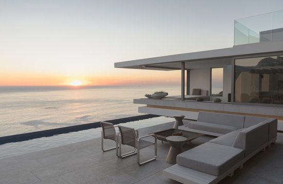 View of sunset over ocean horizon from modern, luxury home showcase exterior patio