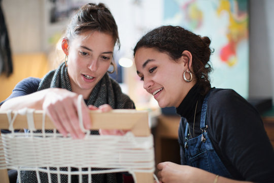 Young women friends making string picture frame art