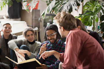 Young adult roommate friends looking at sketchbook in living room