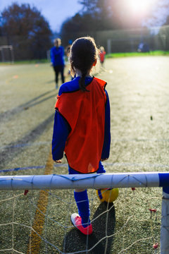 Girl playing soccer on field at night
