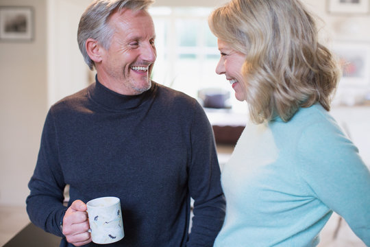 Smiling mature couple talking and drinking coffee