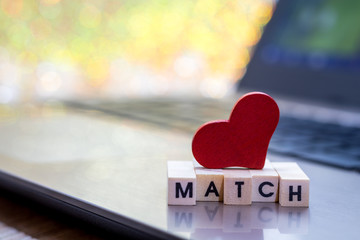Online Dating concept with laptop red heart shape and wood word match