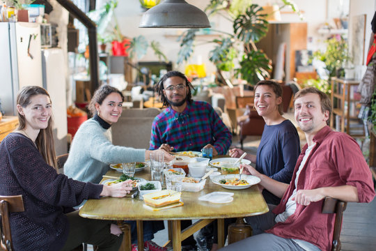 Portrait smiling, confident young adult roommate friends enjoying lunch at apartment table