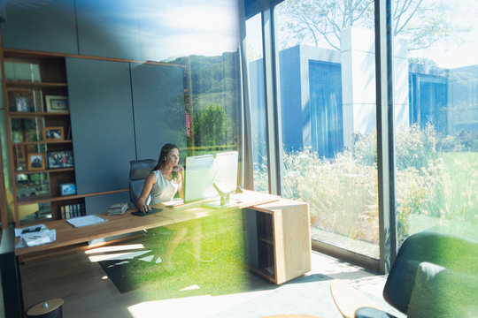 Businesswoman working at computer in sunny home office