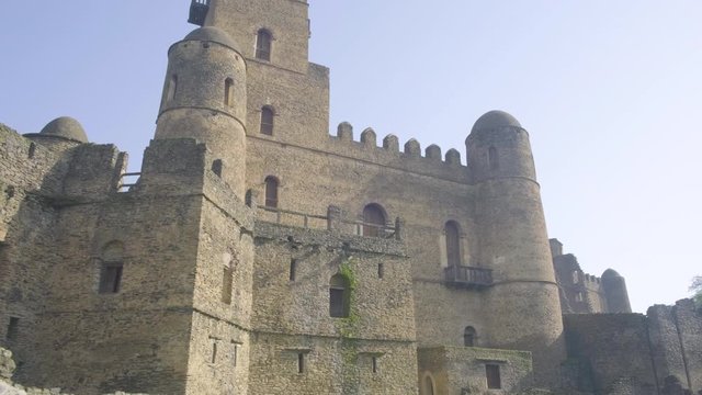 Camera tracking right across a low angle view of Fasilides Castle southern facade in Gondar, Ethiopia
