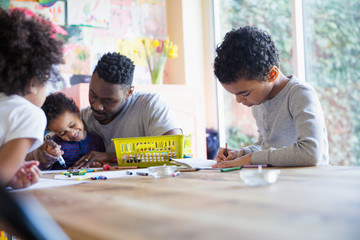 Father and children coloring at table