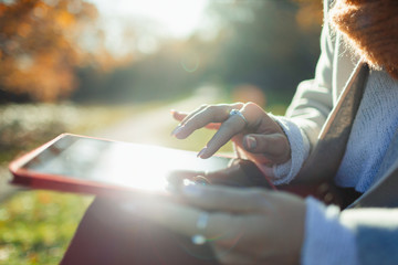 Close up woman using digital tablet in sunny autumn park