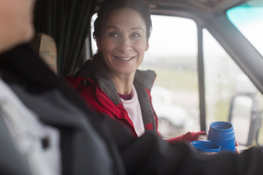 Smiling woman drinking coffee in motor home