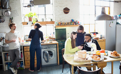 Young adult roommate friends enjoying breakfast in apartment kitchen