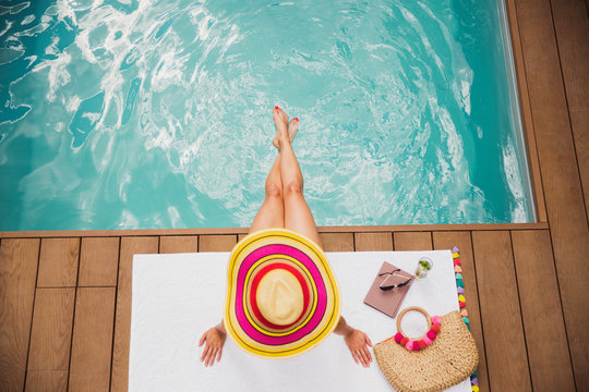 Woman in sun hat relaxing at summer poolside