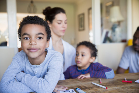 Portrait confident boy coloring with family at table
