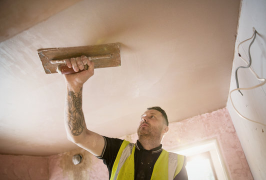 Construction Worker With Tattoo Plastering Ceiling