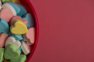 Colorful heart shaped candy in red bowl on top of pink surface , valentine's day love concept