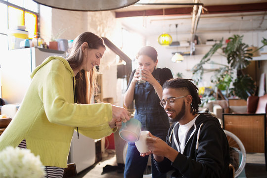 Young adult roommates enjoying tea in loft apartment