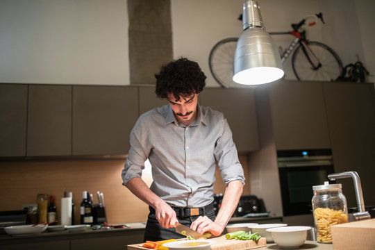 Man cutting vegetables, cooking dinner in apartment kitchen
