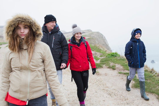 Family in warm clothing walking on snowy winter cliff path