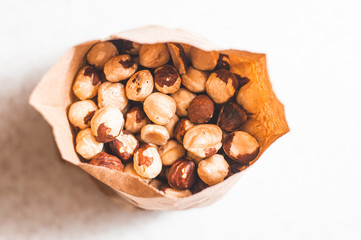 The daily rate of hazelnuts for an adult is packed in a brown paper bag on a white table. View from above.