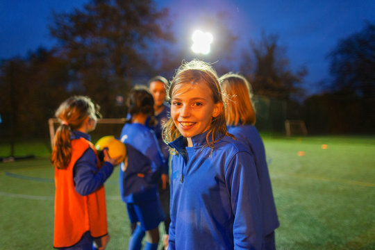 Portrait smiling, confident girl soccer player on field at night