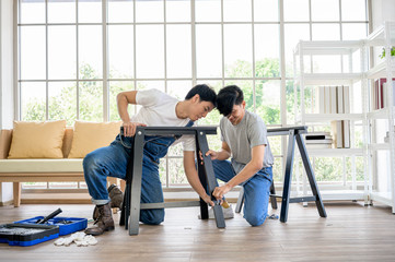 Asian man carpenter working on woodworking table in home carpentry shop. Adult asian man works in home carpentry shop.