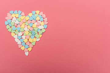 Colorful heart shaped candy on top of pink surface , valentine's day love concept