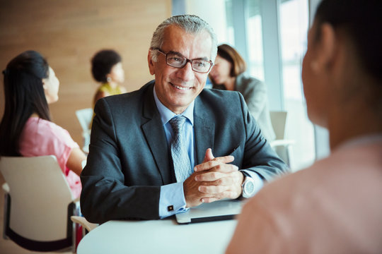 Smiling businessman listening to colleague in cafeteria