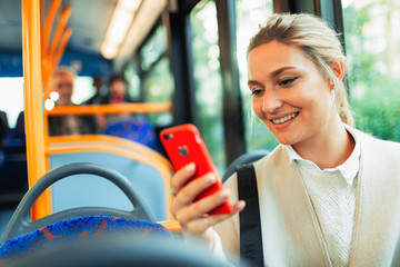 Smiling young woman using smart phone on bus