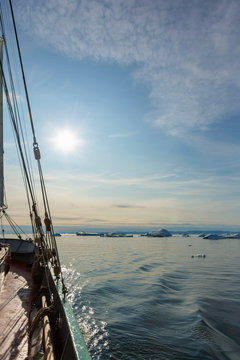 Ship sailing toward icebergs on sunny idyllic Atlantic Ocean Greenland