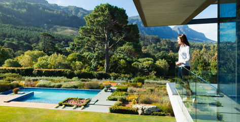 Woman standing on sunny, luxury balcony overlooking swimming pool and landscape, Cape Town, South Africa
