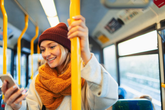 Young woman texting with smart phone on bus