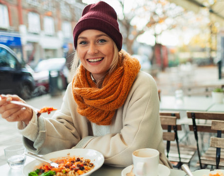 Portrait smiling woman eating lunch at autumn sidewalk cafe