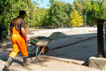 Worker in uniform with a dolly for transportation of materials at street construction works.