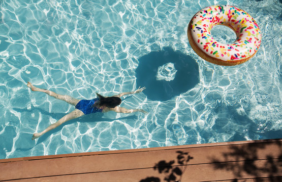 Girl swimming underwater in sunny swimming pool